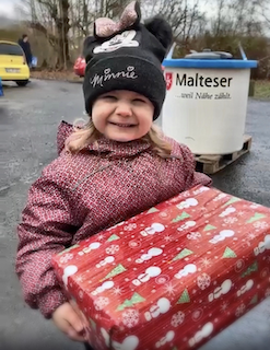 Kind hält Weihnachtspäckchen in der Hand. Die Flüchtlingshilfe am Kirchort Sankt Joseph kann Weihnachten 2022 vielen ukrainischen Kindern eine Freude machen.